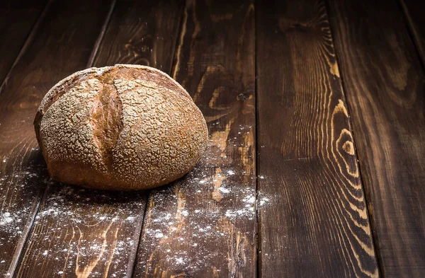 Geleneksel yuvarlak çavdar ekmeği ve patates koyu ahşap bir masa üzerine un serpiştirildi. Karanlık arka plan. Aile sevgisiyle hazırlanmış sağlıklı yemek konsepti, kopyalama alanı.