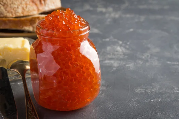 Cam bir kavanozdaki taze somon havyarı. Arka planda, fotokopi alanı olan gri bir arka plan. Tatillerde krep, ekmek ve tereyağıyla servis edilir. Rusya 'da tüm yıl boyunca kullanılır.