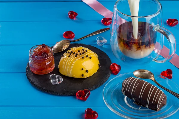Cakes for St. valentine\'s day, Mother\'s Day, or Birthday: Chocolate Cake Potatoes and Mango and Passion fruit Mousse Cake on a blue wooden background with heart decoration. Selective focus, copy space
