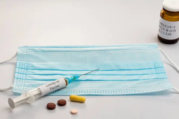 Covid-19 'un yeni versiyonu, Omicron. Koronavirüsün Omicron versiyonu. SARS-CoV-2 varyasyonu. Maske, şırınga, beyaz arka planda izole edilmiş haplar. Boşluğu kopyala, dikkati dağıt