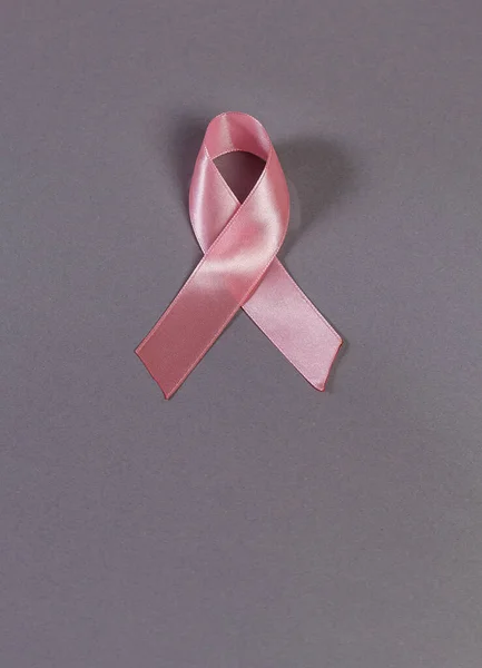 Gri üzerine pembe kurdele, üst manzara. Göğüs kanseri farkındalığı ayı sembolü. Kadın sağlığı konsepti. Kanserle mücadele kampanyasını destekliyorum. Uzayı kopyala Defoktus. Dünya Kanser Günü