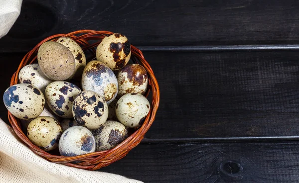 Hasır sepette taze bıldırcın yumurtası. Koyu ahşap arka planda taşra tarzı. Üst görünüm, yakın çekim, seçici odak
