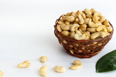 Hasır sepette beyaz arka planda kurutulmuş kaju fıstığı. Boşluğu kopyala