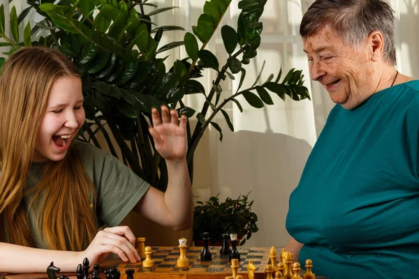 Büyükanne, torunuyla evde satranç oynarken iyi eğlenceler. Strateji ve planlama konsepti. Yaşlılar için etkinlikler, yaşlılar için aktif yaşam tarzı, yaşlılar için zaman harcama konsepti. Seçici odak