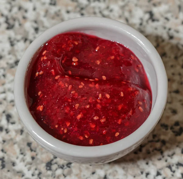 Ahududu reçeli, küçük bir kasede, taş bir masanın üstünde. kopyalama alanı, seçici odak