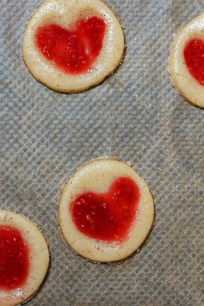 Fırın tepsisinde ahududu reçeli karamelli kurabiye hamuru. Aşçılık süreci adım adım. Altıncı adım. Hamurdaki kalbi çıkar. Girintiye reçel ekle. Seçici Odaklanma.