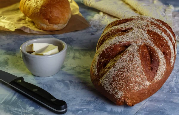 Kırsal tarzda. Yan manzara, yatay, gri arka planda çavdar ekmeği ve tereyağı. Çeşitli ekmek seçimleri. Ekmek ve tereyağlı kahvaltı veya aperatif, seçici odaklanma