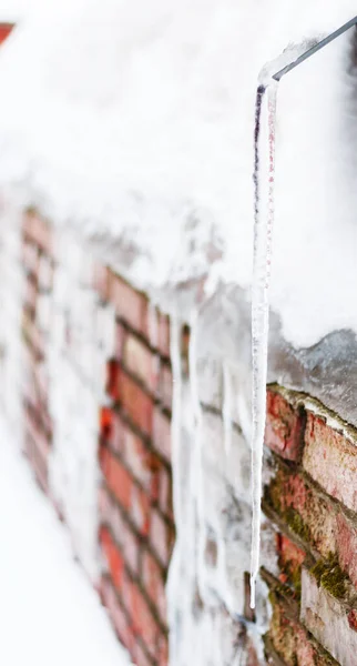 Duvardaki uzun ince buz sarkıtı, bulutlu bir gün, seçici odak, boşluğu kopyala