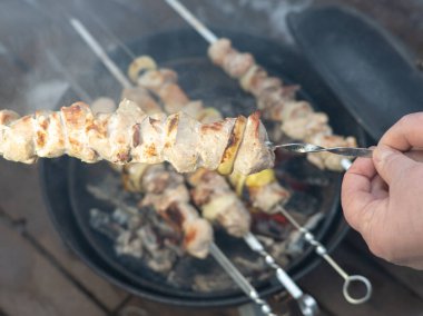 El kebabı çevirir. Kesilmiş fotoğraf. Barbeküde et kızartıyoruz. Yukarıdan görüntüle.