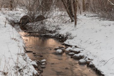 Karlı yollarda küçük bir dere.