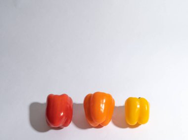 Üç biber, sarı, kırmızı, beyaz arka planda turuncu. Metin için boşluk var