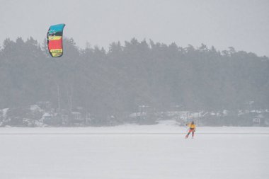 Finlandiya. Espoo 'da. 29 Ocak 2022. Denizde kayak yapan bir uçurtma sörfçüsü, kötü hava, güçlü rüzgar ve kar fırtınası.