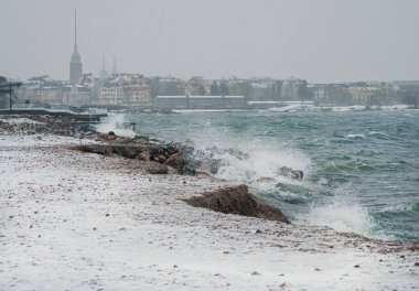 Kış fırtınasında Helsinki 'nin kıyı manzarası, kayalık bir sahilde dalgalar kırılıyor. Finlandiya hava durumu