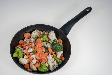 Arka planda kızarmış tavada donmuş sebzeler. Arka plan, üst manzara. Metinler için bir yer var. Lahana, havuç..