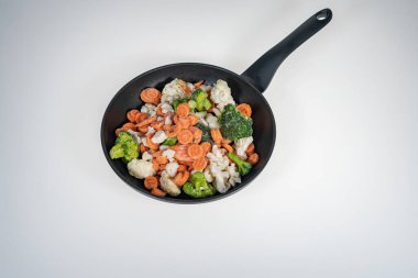 Arka planda kızarmış tavada donmuş sebzeler. Arka plan, üst manzara. Metinler için bir yer var. Lahana, havuç..