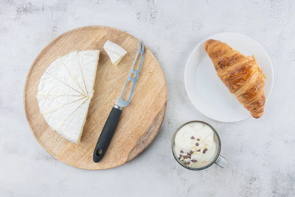 Bir fincan kahve, tereyağlı çörek, peynir bıçağı ve tahta tabakta dilimlenmiş beyaz peynir. Ev kahvaltısı