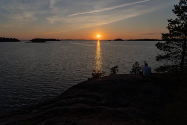 Denizde gün batımı, kayalar ve kuzey alçak çam ağaçları. Finlandiya doğası. Turku. Tatil, tatil, rahatlama konsepti