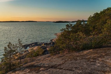 Gün batımında deniz manzarası, kayalar ve kuzey alçak çam ağaçları. Finlandiya doğası. Turku. Tatil, tatil, rahatlama konsepti