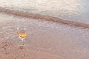 Deniz kenarında bir bardak beyaz şarap. Kumsal, yaz günü..