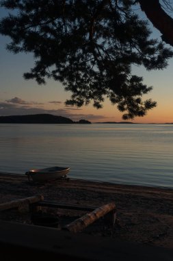 Deniz burnu ve kıyıda bir tekne. Huzurlu, sakin, akşam gökyüzü ve deniz. Doğal arka plan. Yaz akşamı..