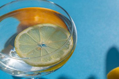 Mavi arka planda limon ve limonlu bardak. Tazelik ve rahatlama kavramı