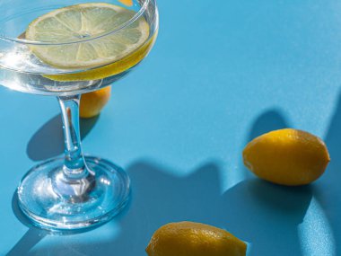 Mavi arka planda limon ve limonlu bardak. Tazelik ve rahatlama kavramı