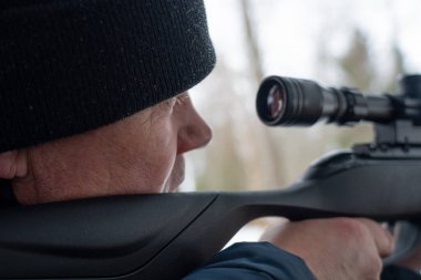 Bahar ormanında tüfekli bir adam, avcı tüfeğini tutar ve avını bekler, avcı ateş eder.