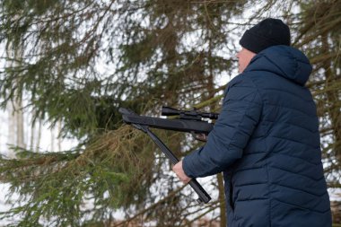 Bahar ormanında tüfekli bir adam, avcı tüfeğini tutar ve avını bekler, avcı ateş eder.