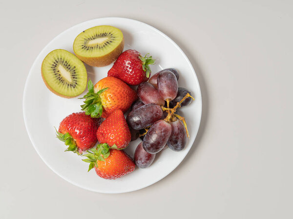 Strawberries and grapes, kiwi on a plate .Concept dissert, vitamins