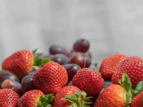 Çilekler ve üzümler üst tarafta. Yakın plan. Tez kavramı, vitaminler.