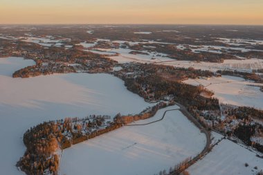 Ormanın üzerindeki manzara ve buzla kaplı göl. Kışın erken doğumu. Drone fotoğrafı. İskandinavya. Finlandiya.