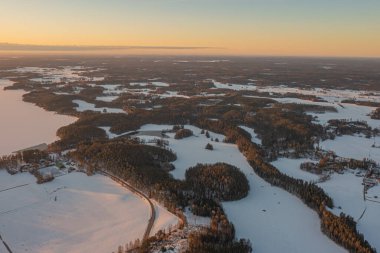 Ormanın üzerindeki manzara ve buzla kaplı göl. Kışın erken doğumu. Drone fotoğrafı. İskandinavya. Finlandiya.