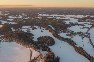 Ormanın üzerindeki manzara ve buzla kaplı göl. Kışın erken doğumu. Drone fotoğrafı. İskandinavya. Finlandiya.