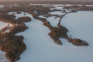 Ormanın üzerindeki manzara ve buzla kaplı göl. Kışın erken doğumu. Drone fotoğrafı. İskandinavya. Finlandiya.