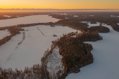 Ormanın üzerindeki manzara ve buzla kaplı göl. Kışın erken doğumu. Drone fotoğrafı. İskandinavya. Finlandiya.
