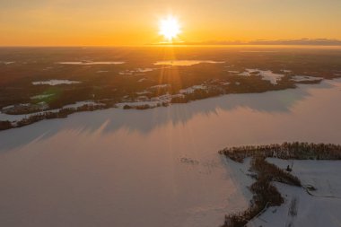 Ormanda gün doğumu ve buzla kaplı göl. Kışın erken doğumu. Drone fotoğrafı. İskandinavya. Finlandiya.