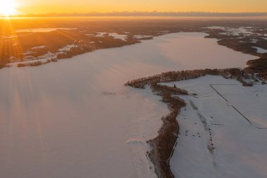 Ormanda gün doğumu ve buzla kaplı göl. Kışın erken doğumu. Drone fotoğrafı. İskandinavya. Finlandiya.