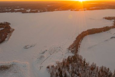 Ormanda gün doğumu ve buzla kaplı göl. Kışın erken doğumu. Drone fotoğrafı. İskandinavya. Finlandiya.
