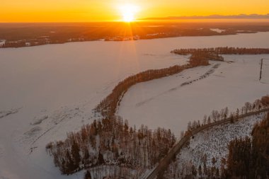 Ormanda gün doğumu ve buzla kaplı göl. Kışın erken doğumu. Drone fotoğrafı. İskandinavya. Finlandiya.