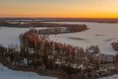 Ormanda gün doğumu ve buzla kaplı göl. Kışın erken doğumu. Drone fotoğrafı. İskandinavya. Finlandiya.