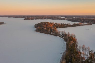 Ormanda gün doğumu ve buzla kaplı göl. Kışın erken doğumu. Drone fotoğrafı. İskandinavya. Finlandiya.