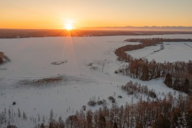 Ormanda gün doğumu ve buzla kaplı göl. Kışın erken doğumu. Drone fotoğrafı. İskandinavya. Finlandiya.