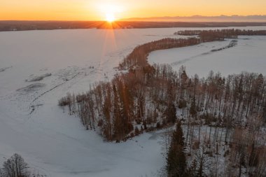 Ormanda gün doğumu ve buzla kaplı göl. Kışın erken doğumu. Drone fotoğrafı. İskandinavya. Finlandiya.