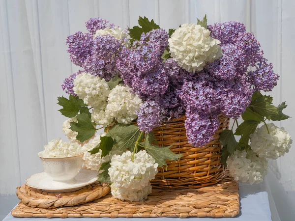 Bouquet Lilacs White Viburnum Basket Tea Set Table Garden Background lizenzfreie Stockfotos