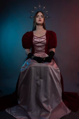 Efsanevi fantezi kraliçesi. Kafasında gümüşi gotik taç var. Burgundy klasik sanatsal elbise. Elf prensesi. Ortaçağ tarzı. Siyah bir anahtarda tam boy portre.