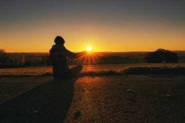 Sonbaharın güzel bir akşamında batan güneşi elinde tutan bir kadın silueti.