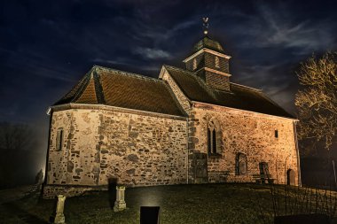 Mezarlığı olan küçük eski bir şapel, geceleri bir tepede aydınlanıyor.