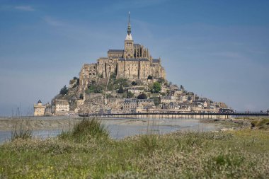 Güneşli bir günde mavi gökyüzü ve çayırlarla ünlü tarihi Le Mont Saint-Michel gelgit adasının panoramik manzarası