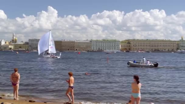 Ciudadanos tomando el sol en las paredes de la fortaleza de Pedro y Pablo observando una regata — Vídeo de stock