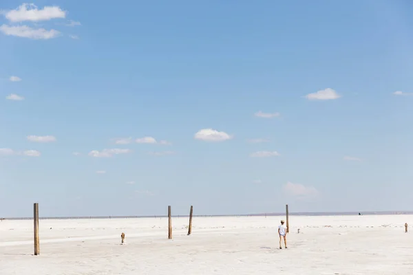Ragazzo solitario cammina sulla superficie di un lago salato a mezzogiorno. Deserto e cielo paesaggio Fotografia Stock